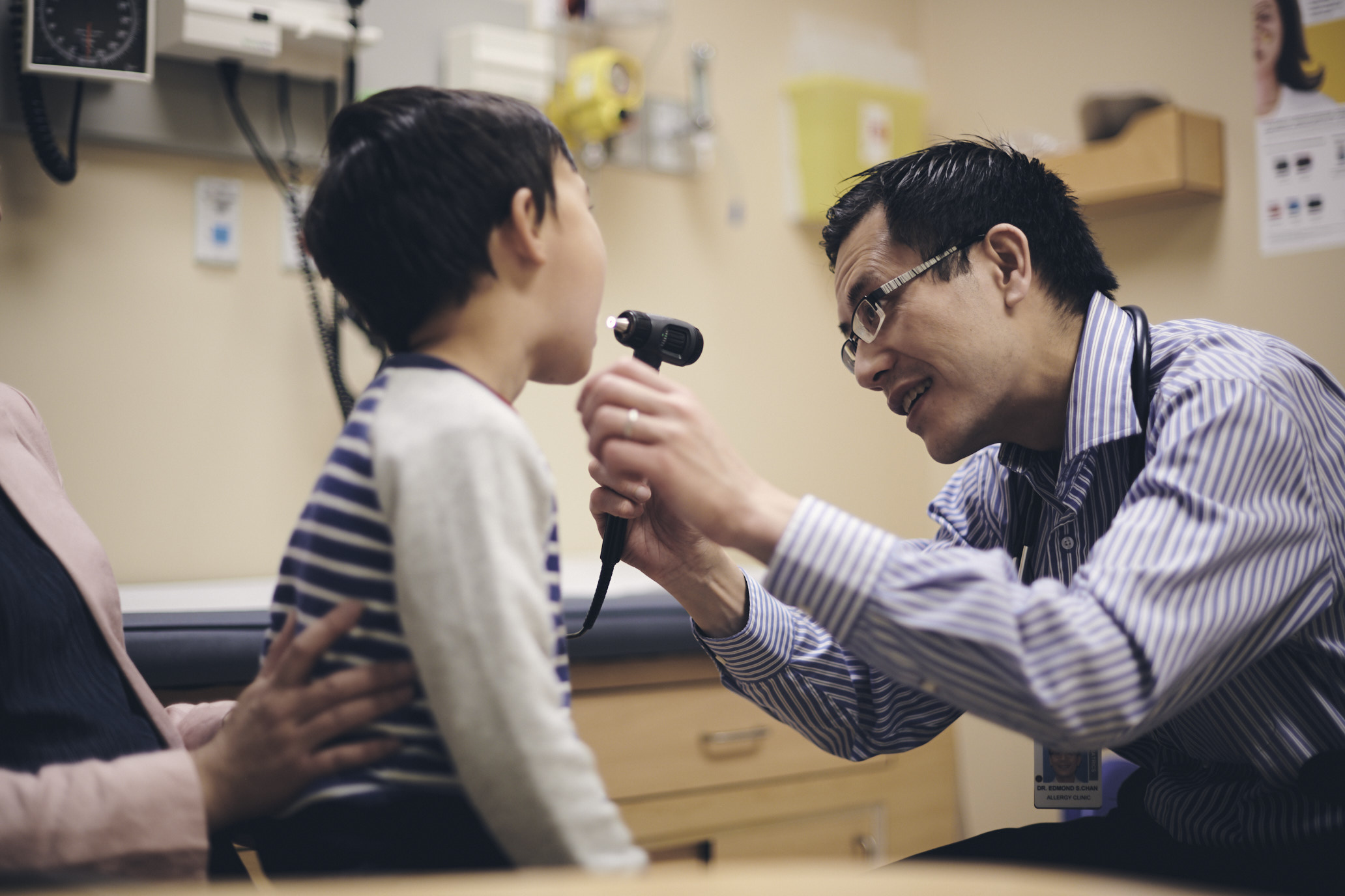 Doctor beams a light into the mouth of a child patient in a medical office