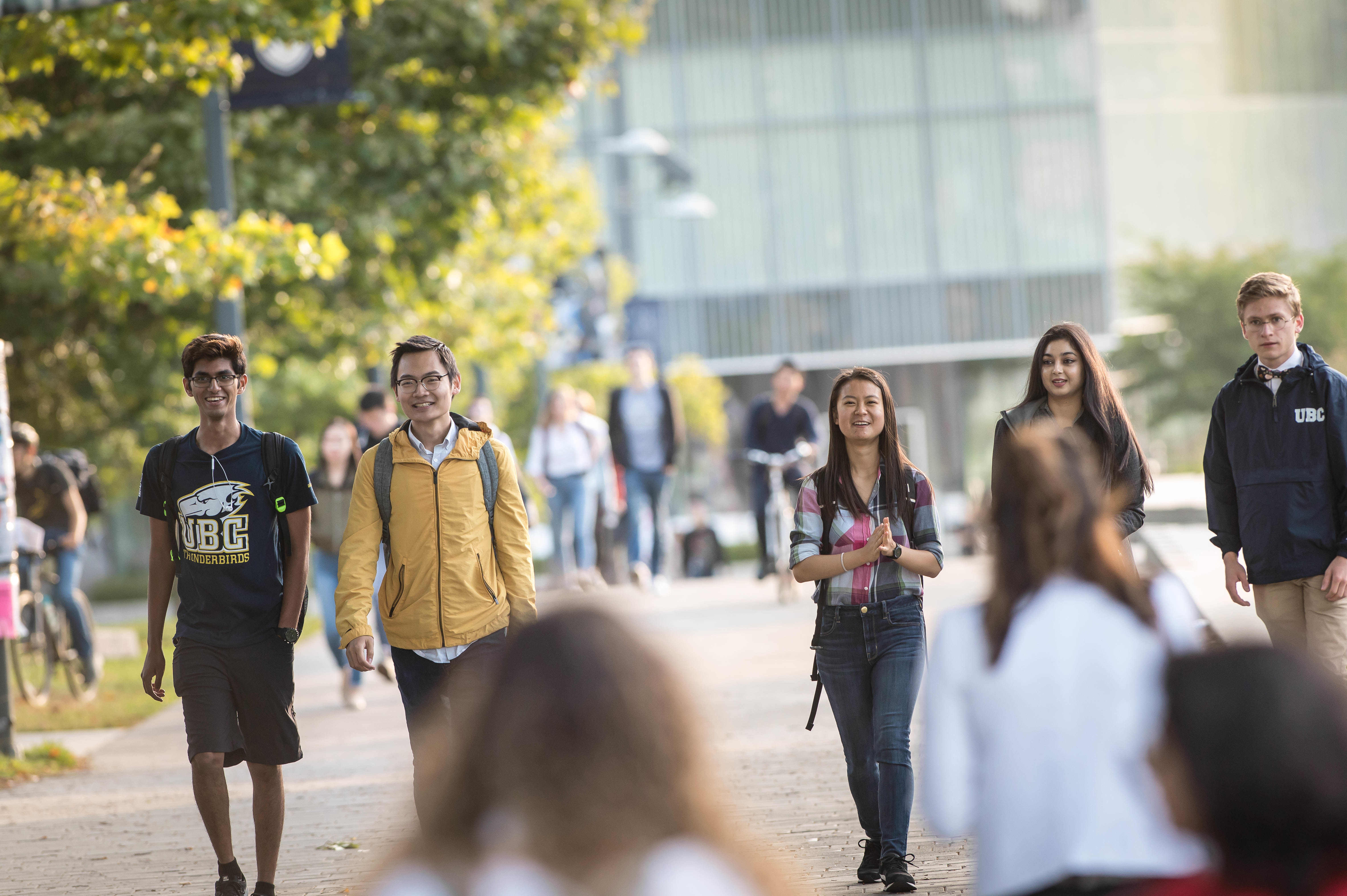 5 UBC students walking on UBC Vancouver campus, with the Robert H. Lee Alumni Centre in the background