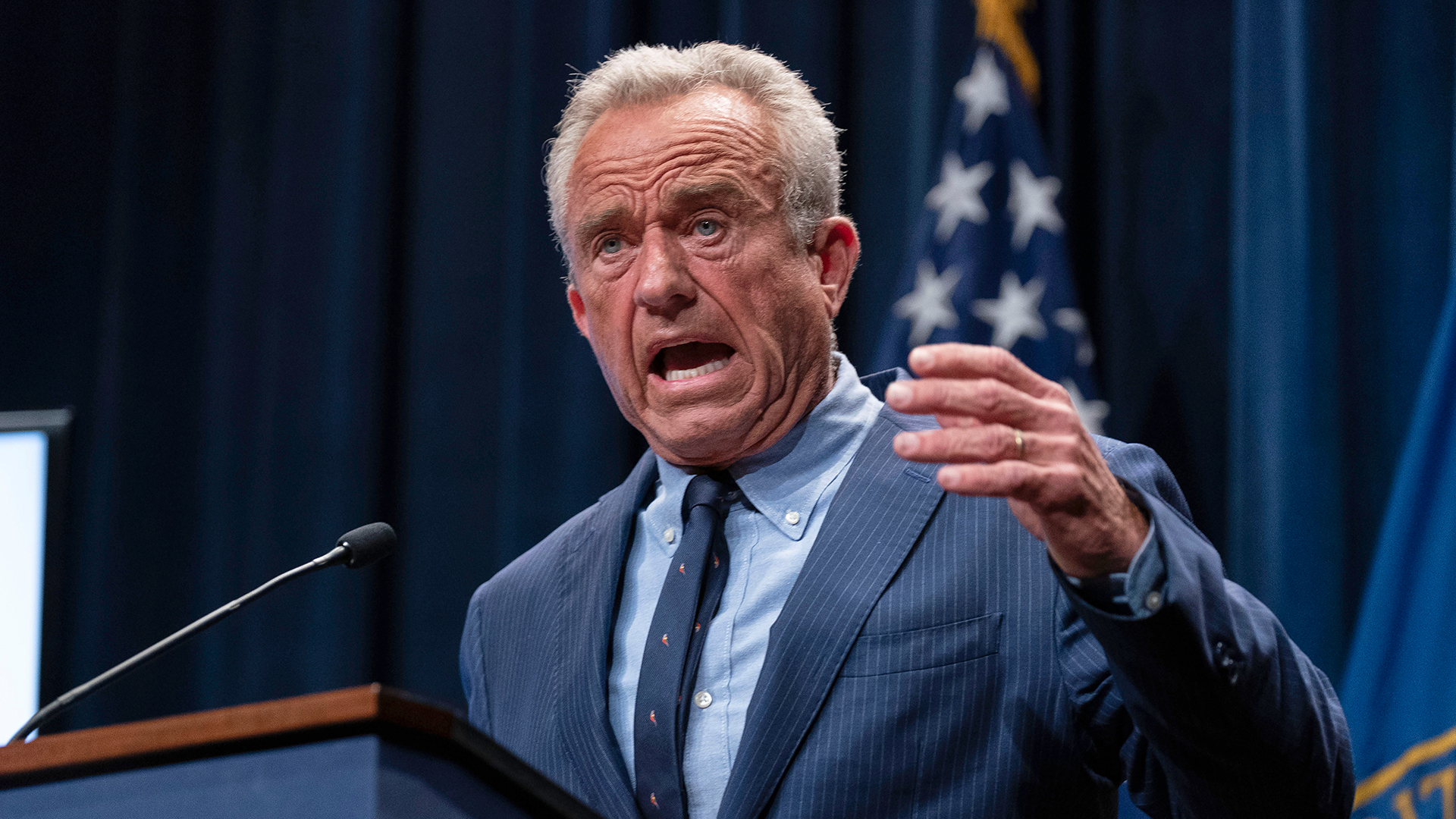Robert F. Kennedy standing at the podium during a news conference on the autism report.