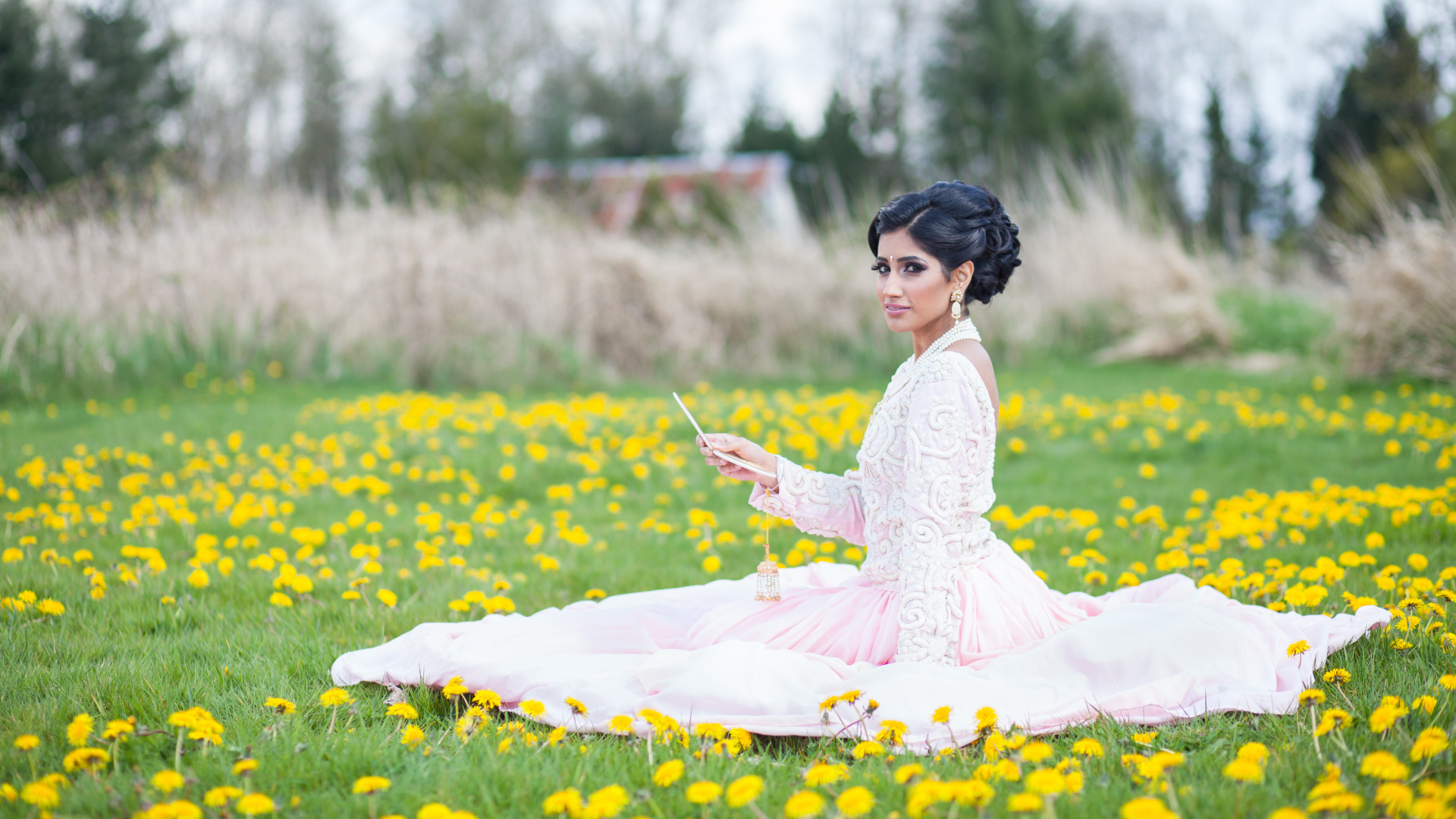 Actor Rami Kahlon in a white dress sitting in a field