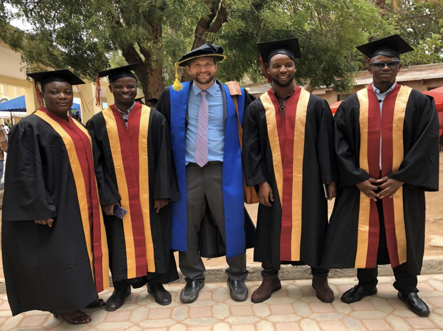 Photo of Freeman Poritz wearing a graduation robe, in between four other people also in graduation robes.