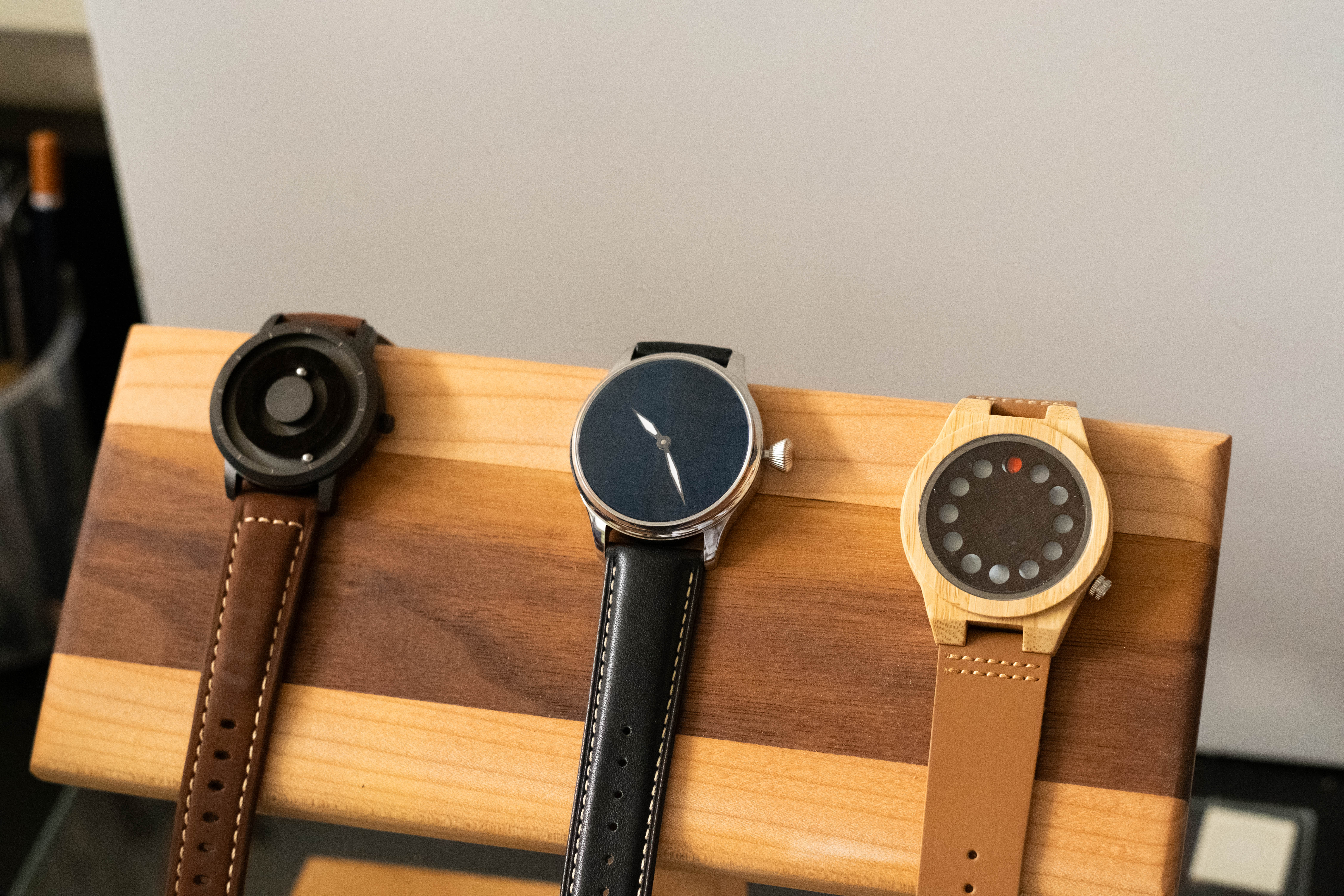 Three watches displayed on wood stand