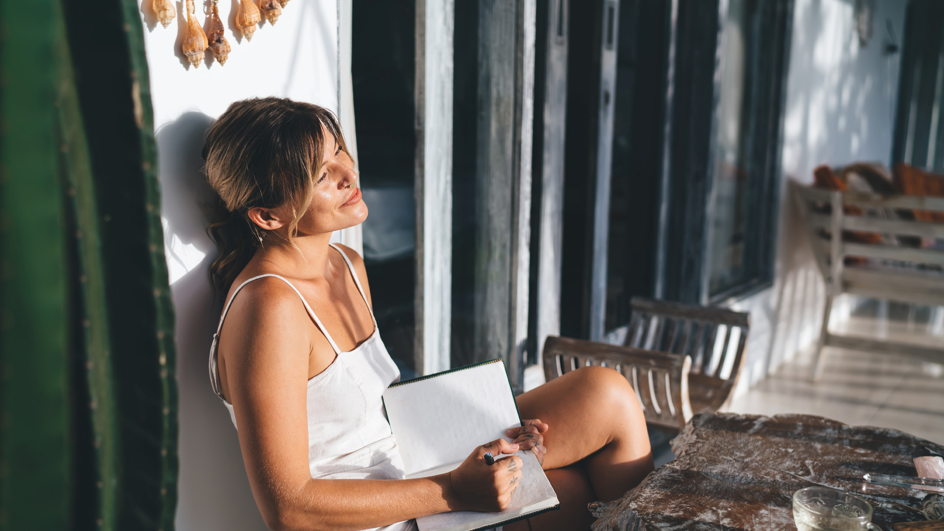 A person looks off into the distance with a pen and notepad on their lap