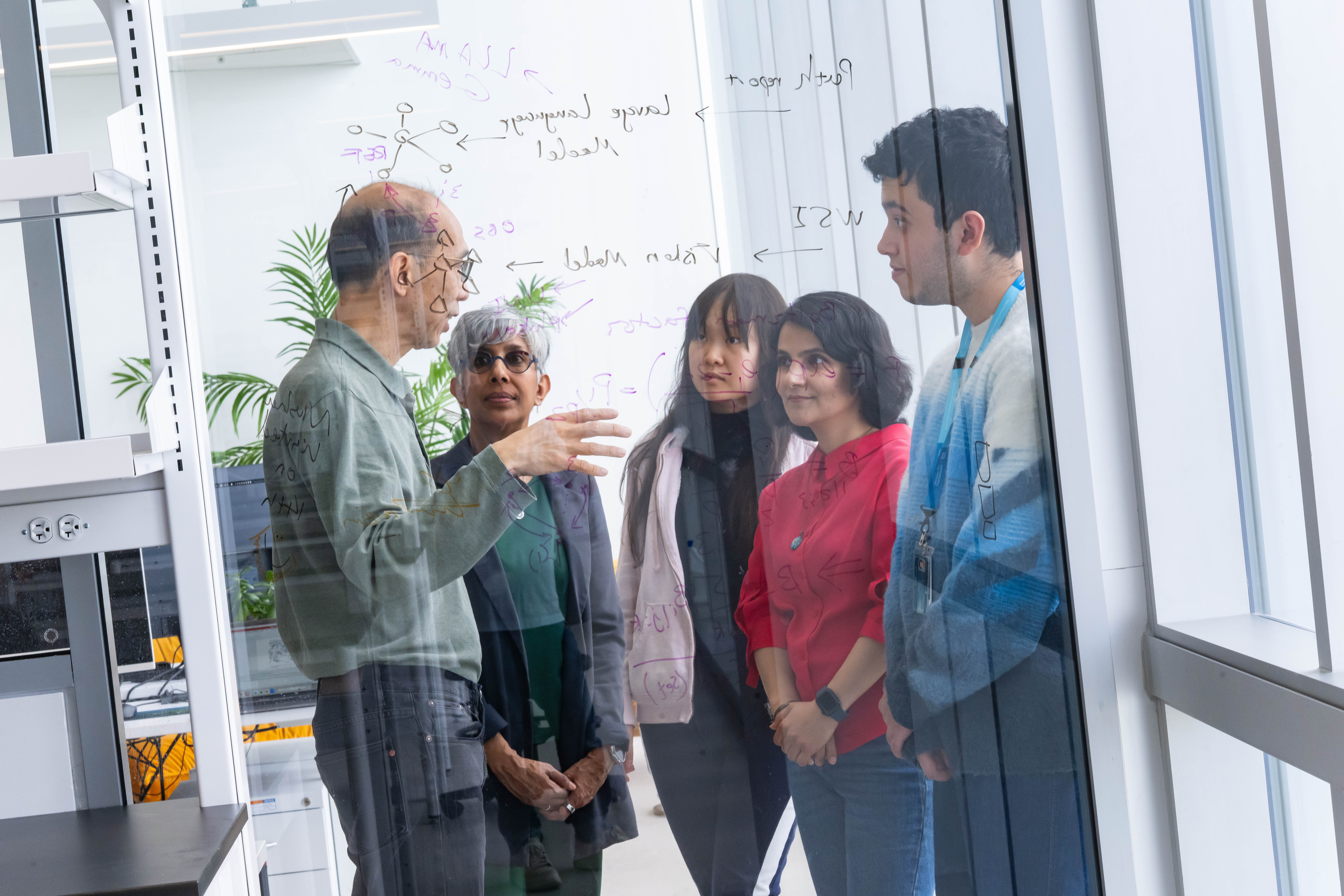 Man and woman speak to three students in a classroom lab