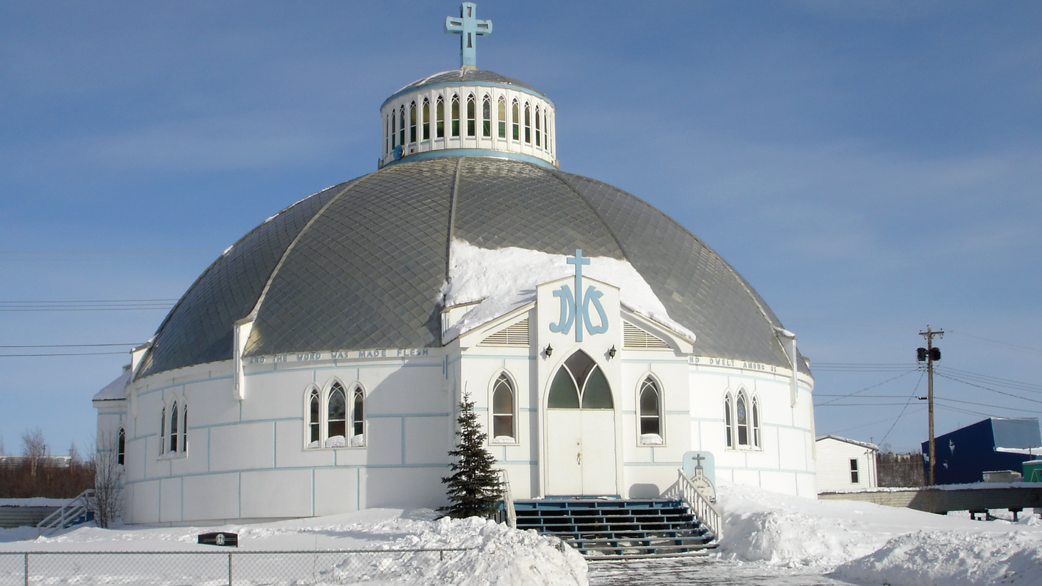 A circular white church with a domed roof, surrounded by waist-high snow