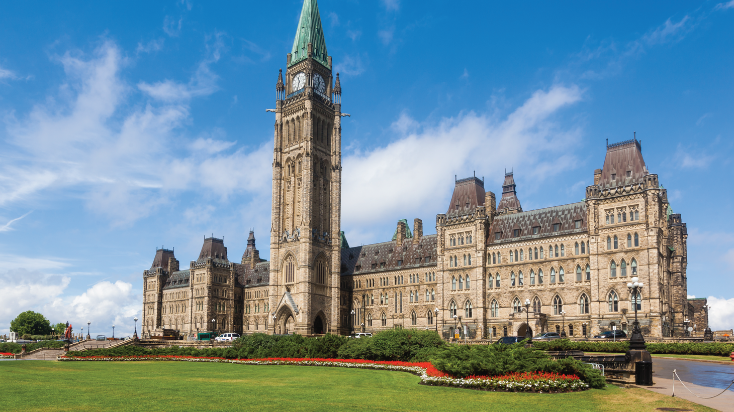 Gothic revival building with clock tower in the center with patinaed turret
