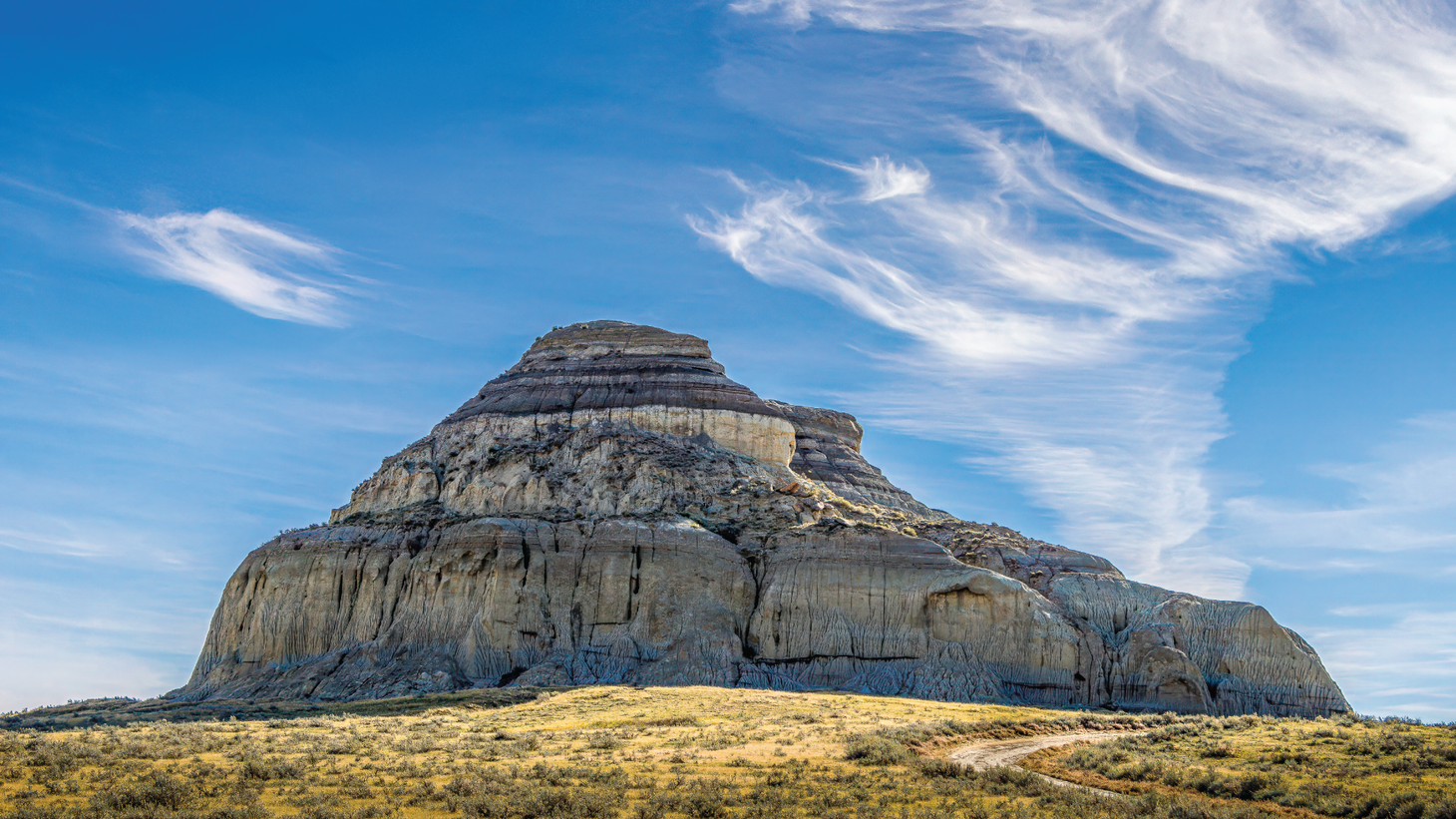 An enormous butte surrounded by scraggy scrubland and open sky