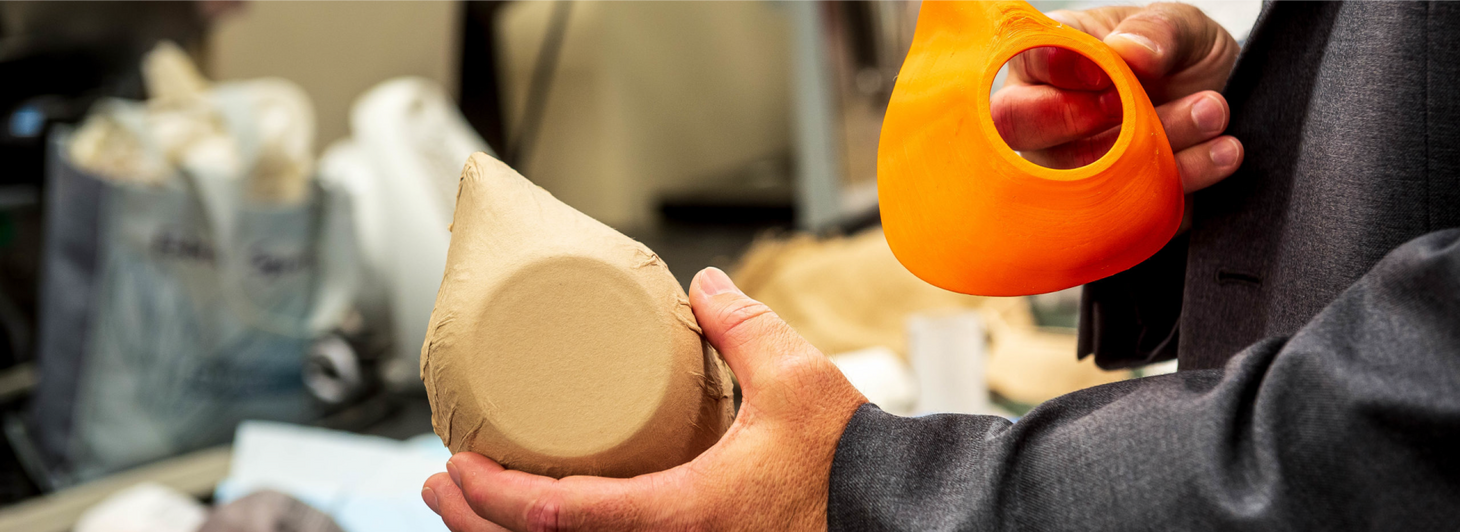 Man holds wood-fibre mask prototype in workshop