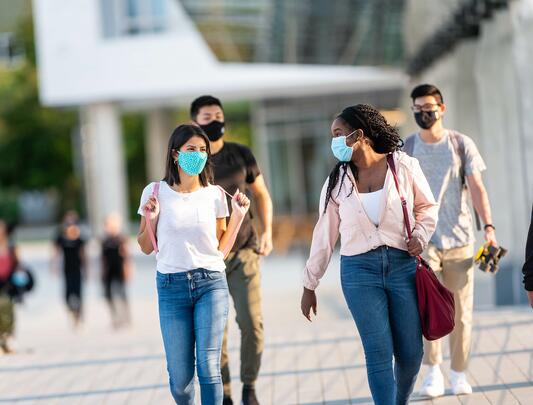 A group of UBC students with masks on walk on campus.