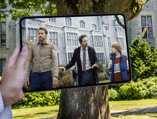 Shot of an iPad screen held over the Chemistry building. On the iPad screen is a shot from the Adam Project outside Chemistry building.