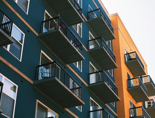 Upward look at series of apartments with balconies at two neighbouring buildings