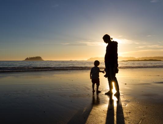 Silhouette of a mother and child on a beach at sunset