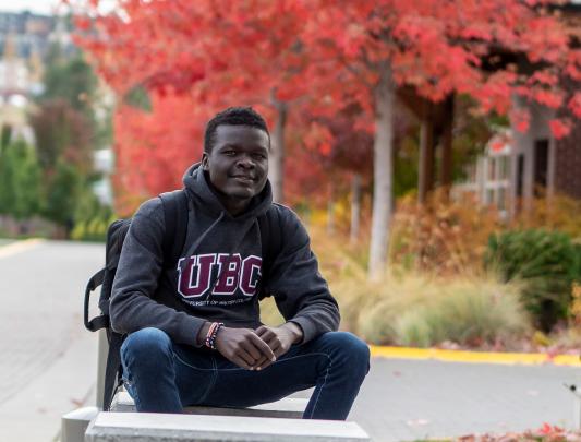 Headshot of James Magok Achuli seated outdoors on UBCO campus on a fall day