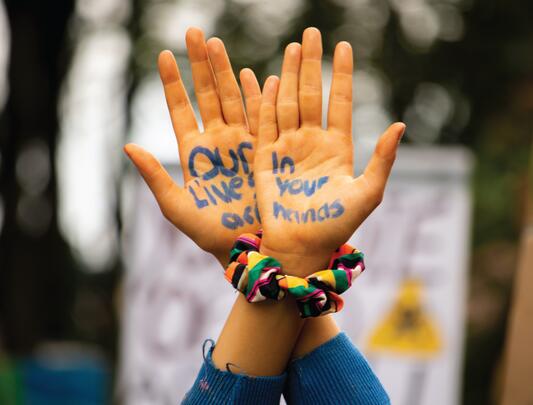 Words written on two hands held in the air at protest
