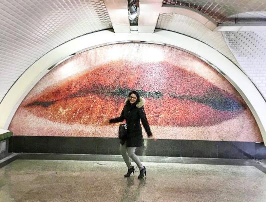 Patricia Gajo posed in front of a large mural depicting red lips