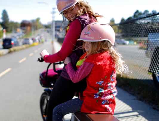 Woman and young girl wearing helmets on bicycle on street