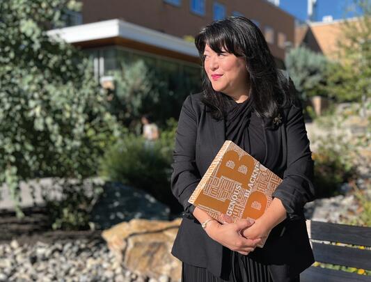 Asian woman holding a book stands in front of a building