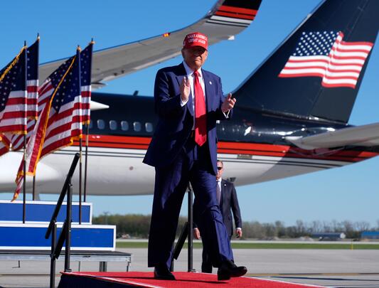 Donald Trump in front of U.S. flags and airplane 