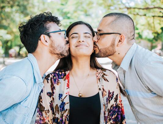 A woman being kissed on either cheek by two people