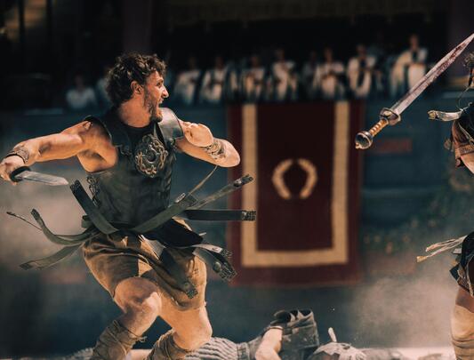 Two male gladiators battle with swords in arena