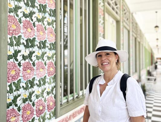 Suzanne Scott headshot, with an angled view of a terrace house with a floral print in the backdrop