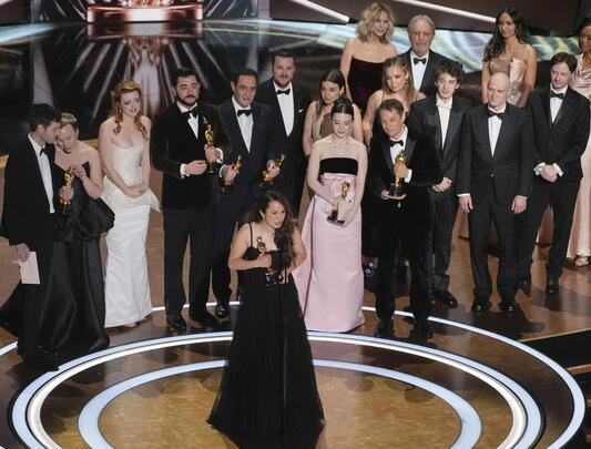 Samantha Quan giving her acceptance speech with the cast and team of her Oscar-winning film behind her
