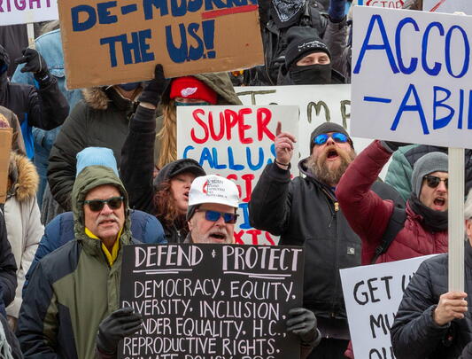 Photo of people protesting and holding up signs. One sign says: "Accountability."