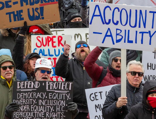 Photo of people protesting and holding up signs. One sign says: "Accountability."