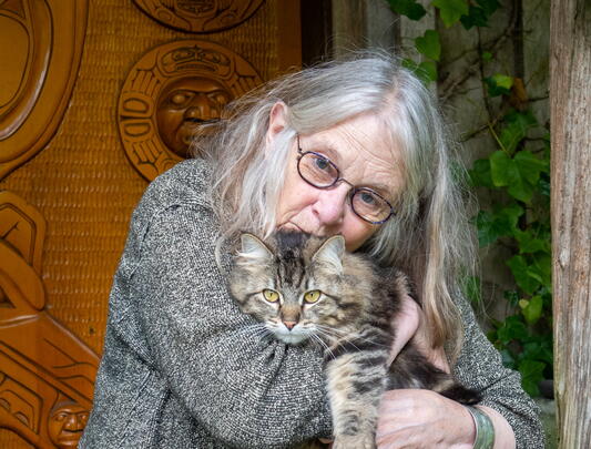 A photo of Susan Musgrave clutching a cat to her chest
