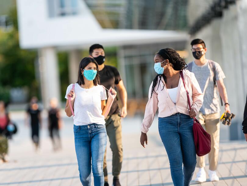 A group of UBC students with masks on walk on campus.