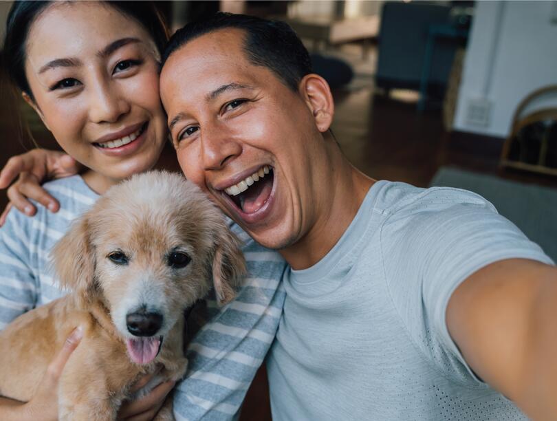 A couple taking a selfie with their puppy