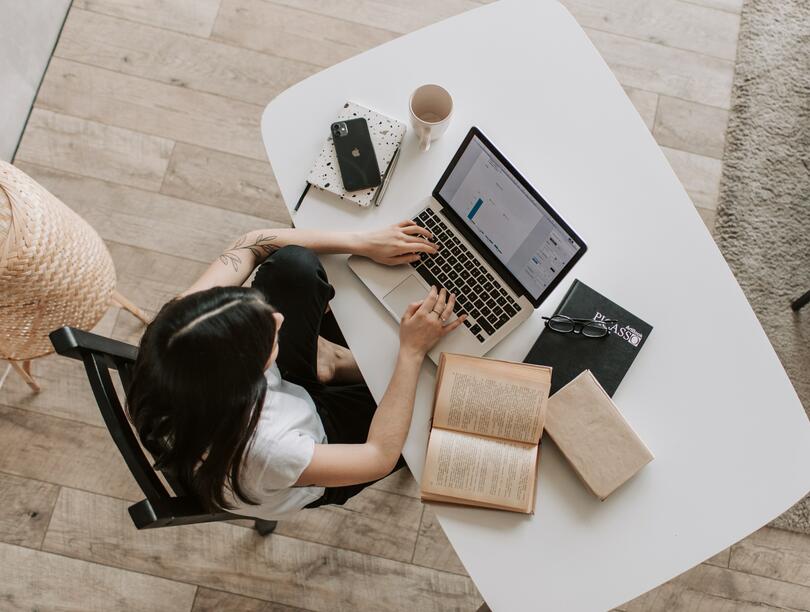 Overhead shot of a student sitting at a desk, typing on her laptop