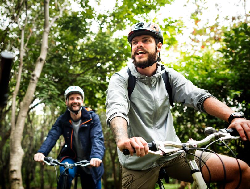 Three men on bikes cycling through a forest