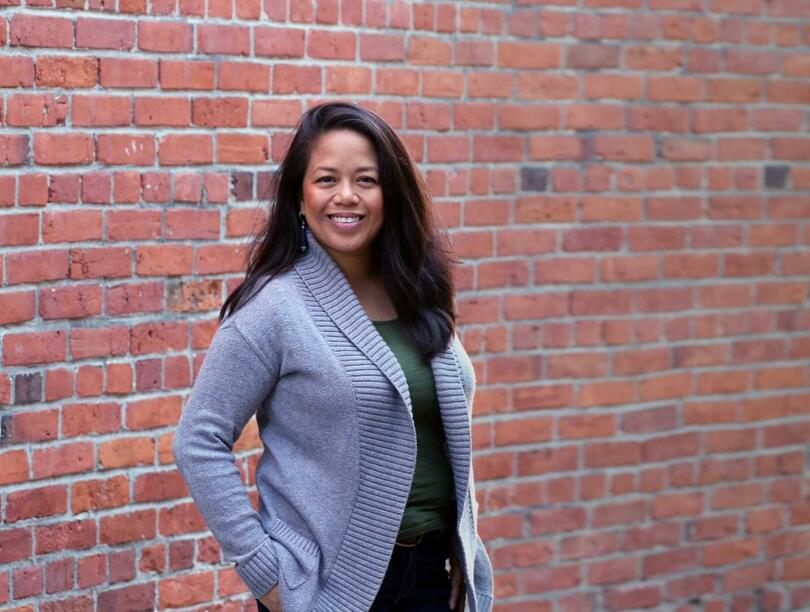Headshot of Charina Cruz, posing in front of a brick wall