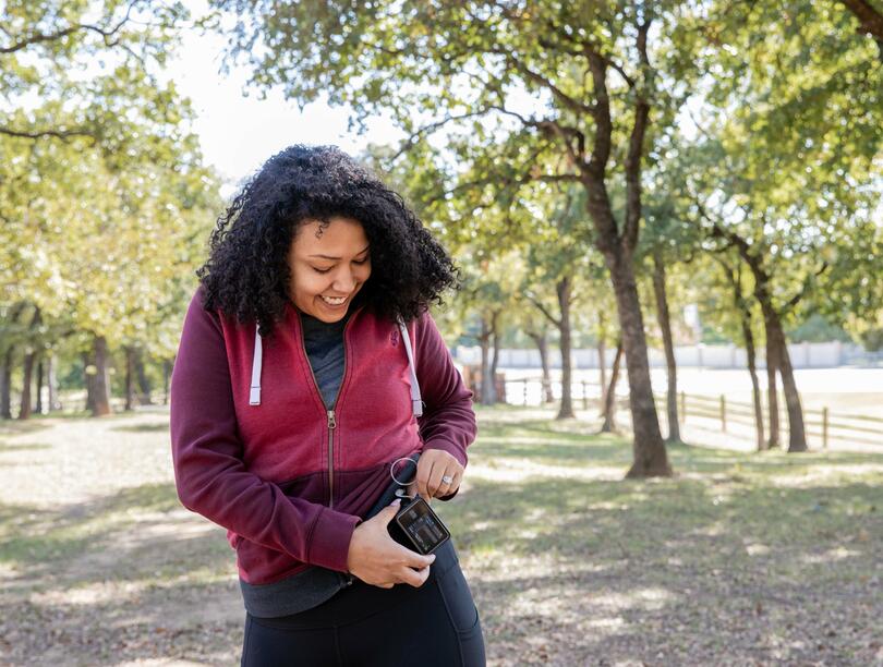 Women in exercise clothes checking a device while out walking