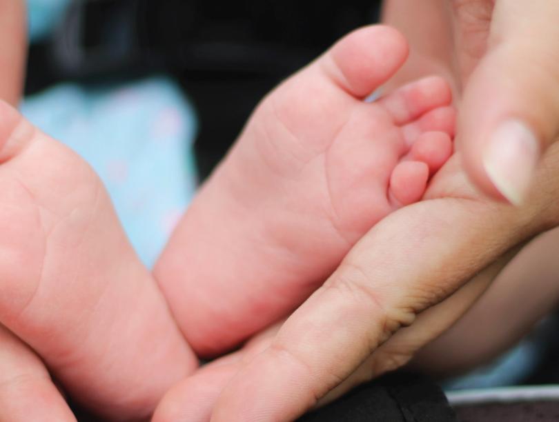 A baby's two feet cradled between an adult's two hands