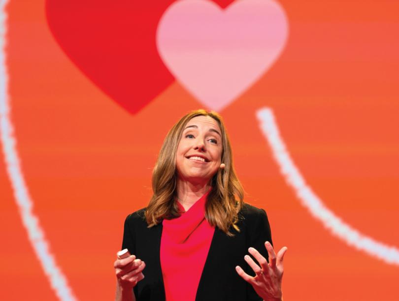 Photo of Dr. Elizabeth Dunn on a stage with a red background