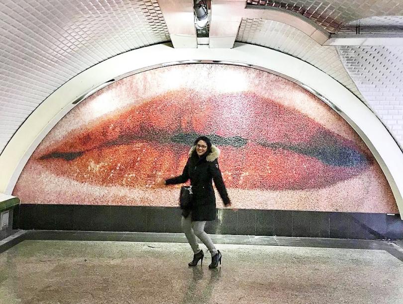 Patricia Gajo posed in front of a large mural depicting red lips