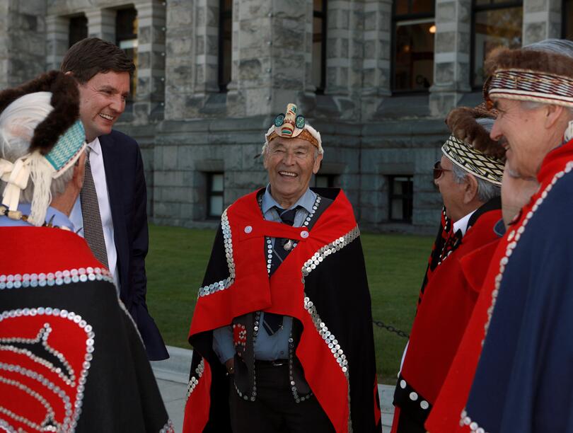 Circle of people in traditional Haida robes in front of building
