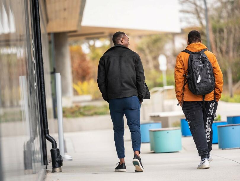 Two people walking together on UBC campus