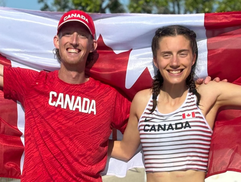 Evan Dunfee and Olivia Lundman, smiling and holding a large Canadian flag behind them