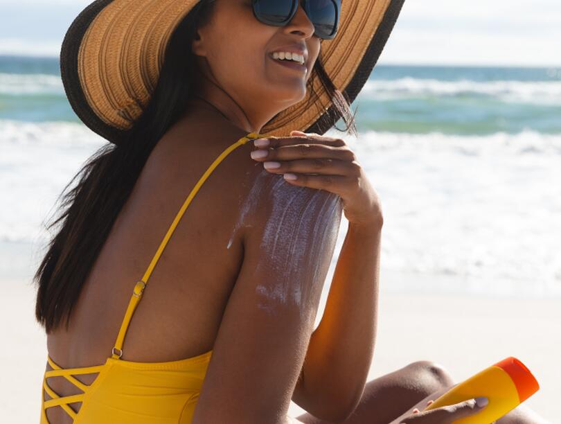 Woman at beach applying sunscreen on herself