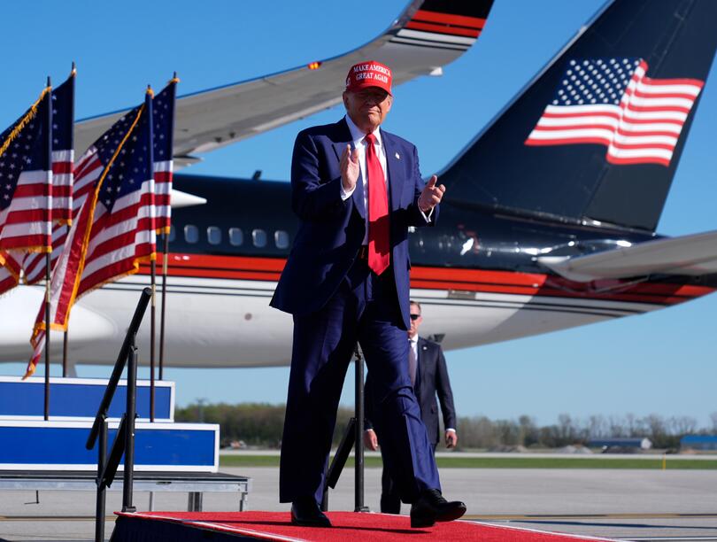 Donald Trump in front of U.S. flags and airplane 