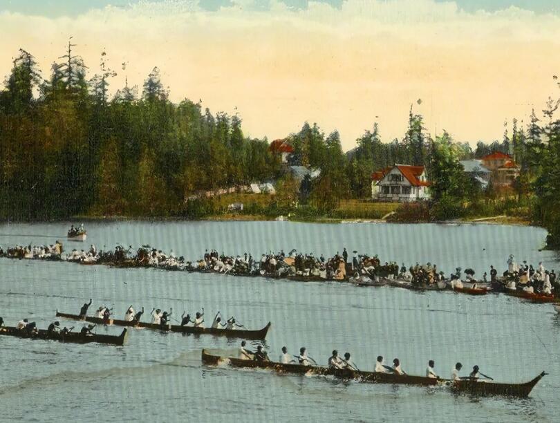 Canoes race past boats with onlookers in Victoria, B.C.