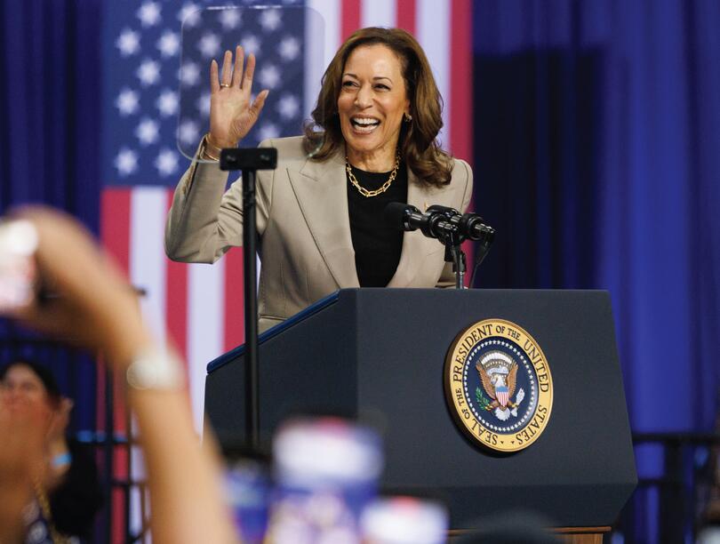 Kamala Harris waves to crowd from podium in front of US flag