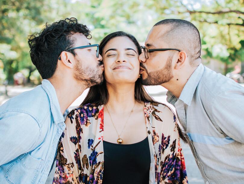 A woman being kissed on either cheek by two people