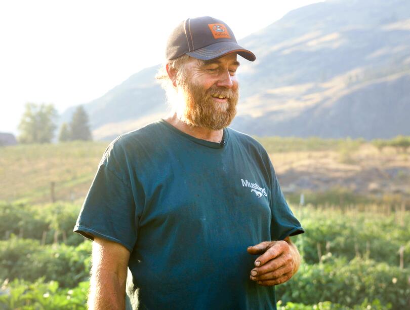 Yuri Zebroff standing on his farm property with mountains in the background