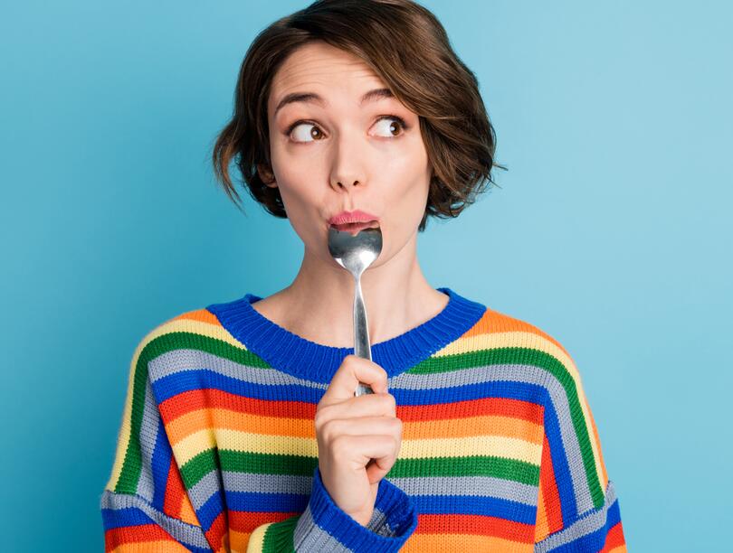 Student holding a spoon in her mouth with a surprised expression