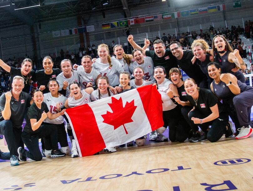 Athletic team cheering and holding Canadian flag in a gym