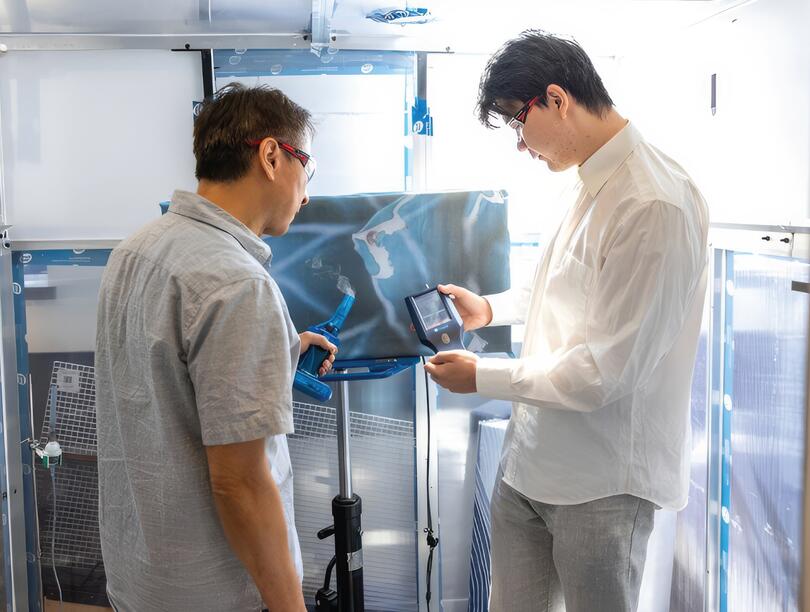 Two men look at device in an industrial lab 